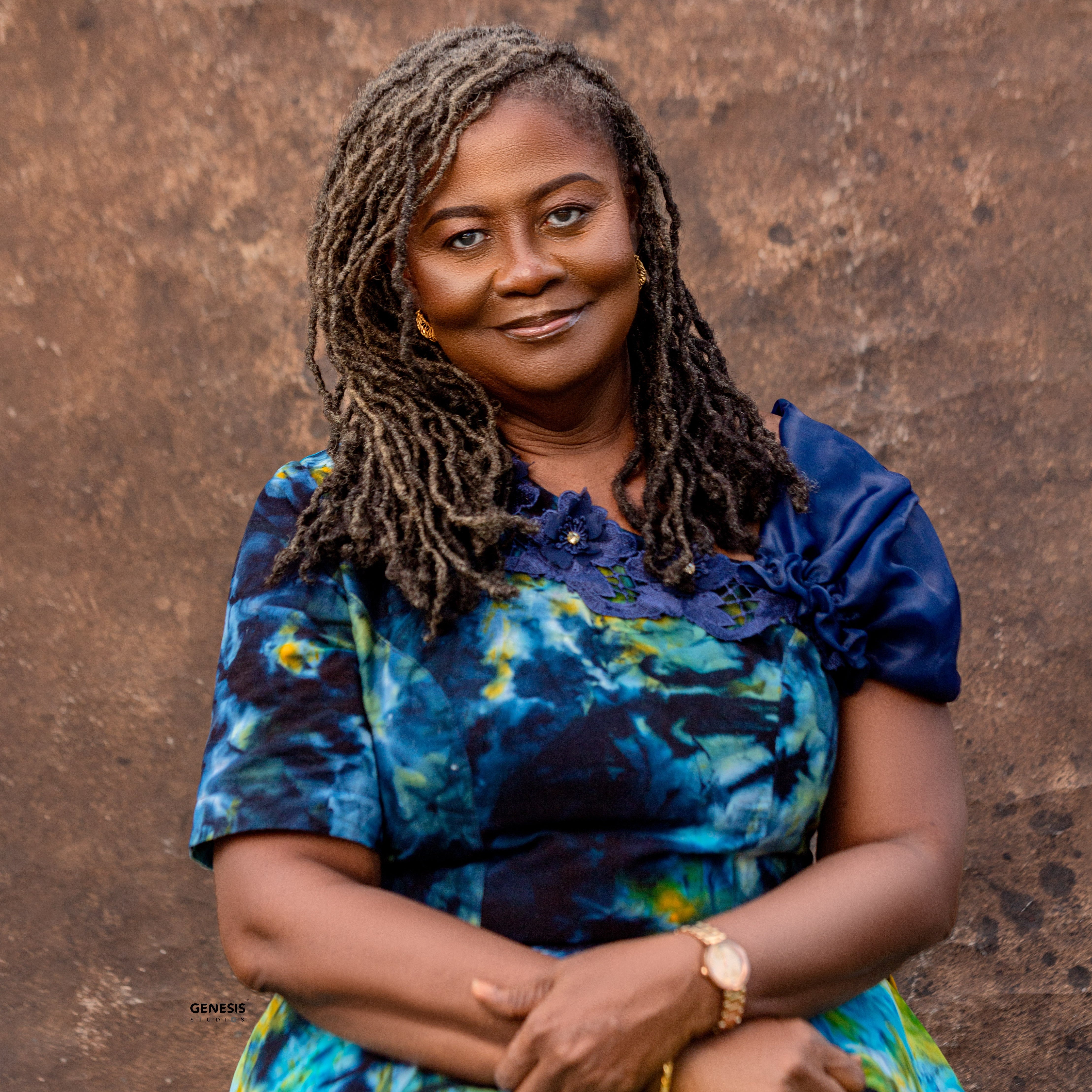 Woman wearing a blue and green patterned dress against a brown background