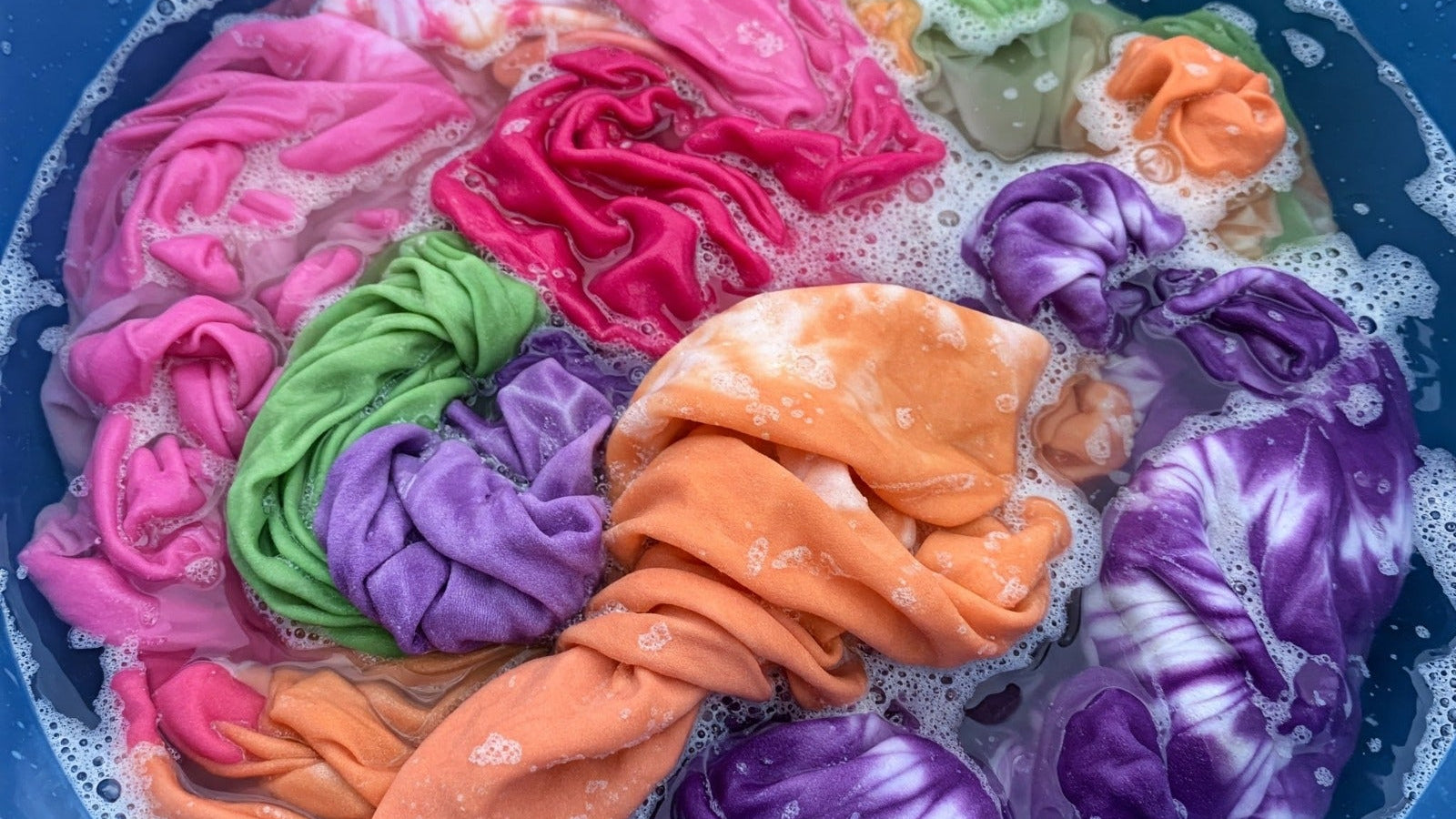 Colorful fabric dyed by Tampoori batik in a blue basin with water and soap bubbles