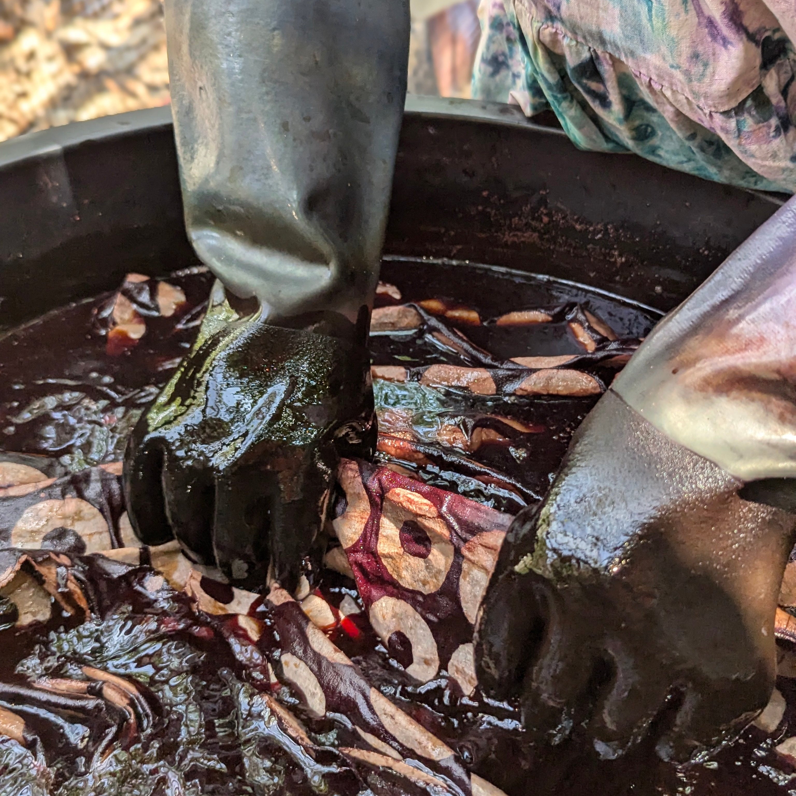 Tampoori textile artisan dyeing fabric in a large vat