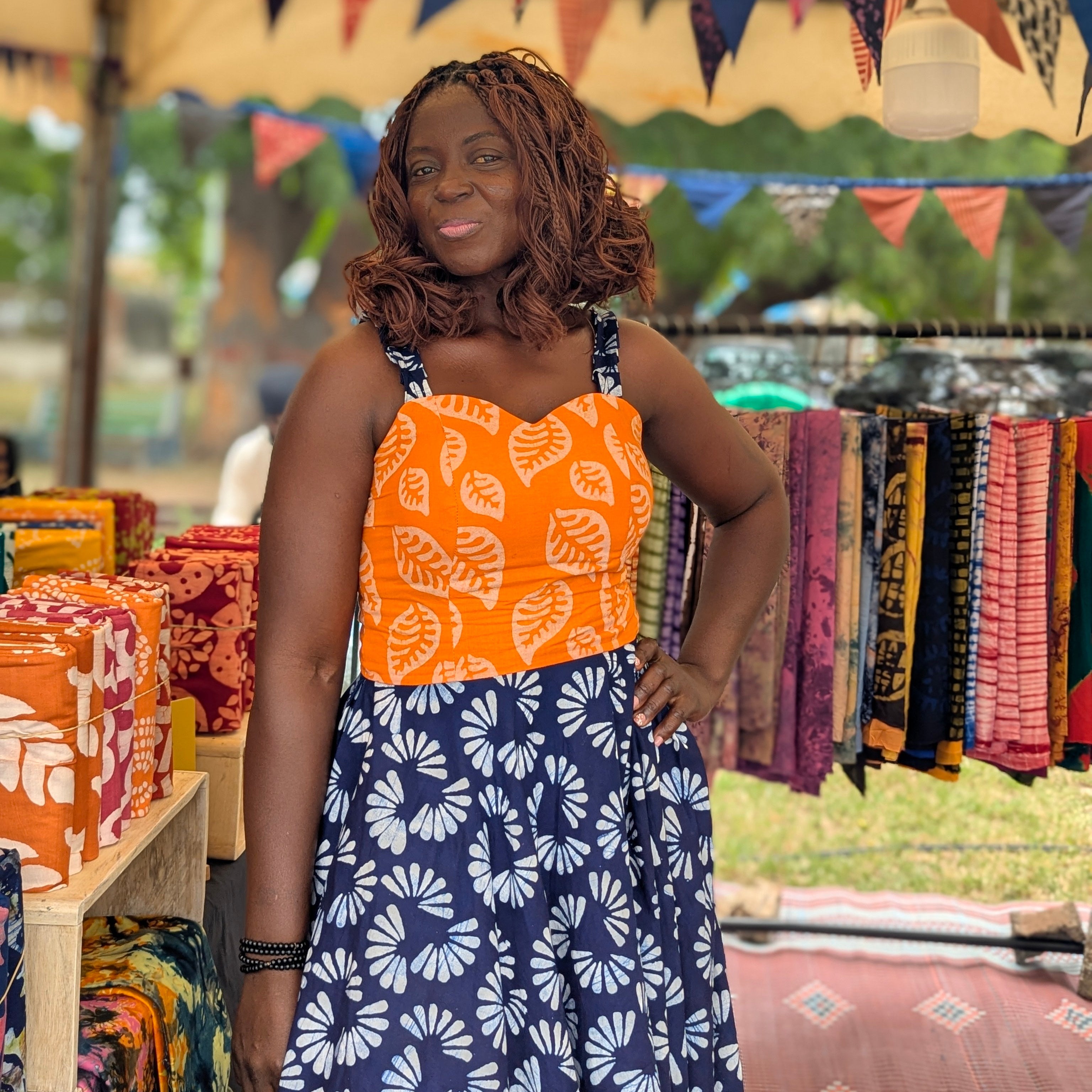Woman standing in front of a colorful market stall with bunting